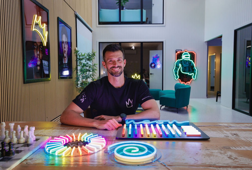Stephen Pastor at a work table surrounded by neon light sculptures